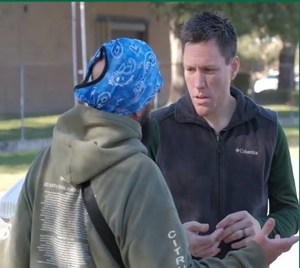 Jason W. Wilson in conversation with a community member outdoors